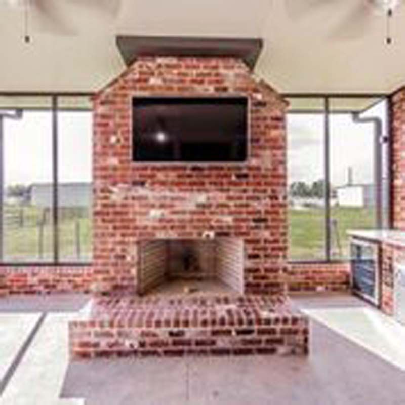 Brick fireplace with mounted TV in a bright, modern indoor patio room