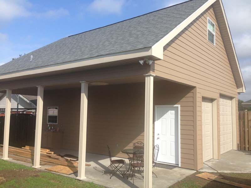 Small tan house with white trim, covered porch, and a white side door under a gray roof.