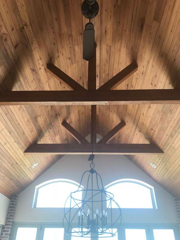 Wooden vaulted ceiling with dark beams and hanging lantern above arched windows