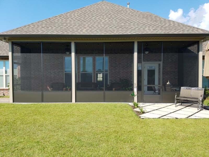 Backyard patio with screened enclosure, grassy lawn, and a small table and chair set