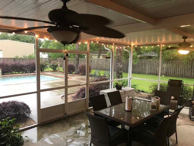 Covered patio with dining table, ceiling fan, and pool view through screened enclosure