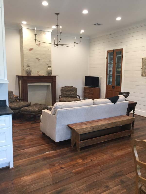 Living room with white sofa, two armchairs, wood floors, fireplace, and rustic bench
