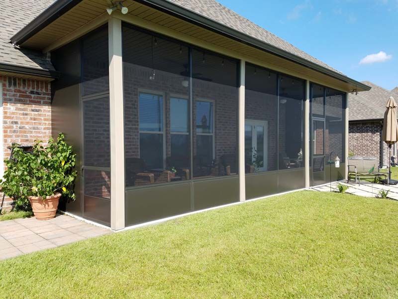 Screened patio attached to a brick house with green lawn in front