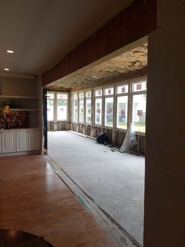Empty room under renovation with exposed ceiling, concrete floor, and large windows along one wall