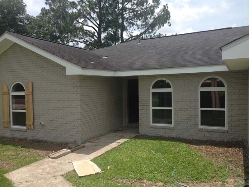 Single-story brick house with arched windows, front entry walkway, and a patchy lawn
