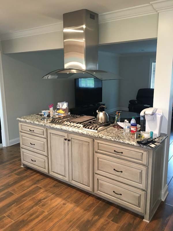 Kitchen island with granite countertop and stainless range hood in a modern home interior