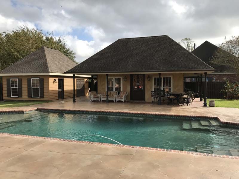 Backyard house with a covered patio and swimming pool under a cloudy sky
