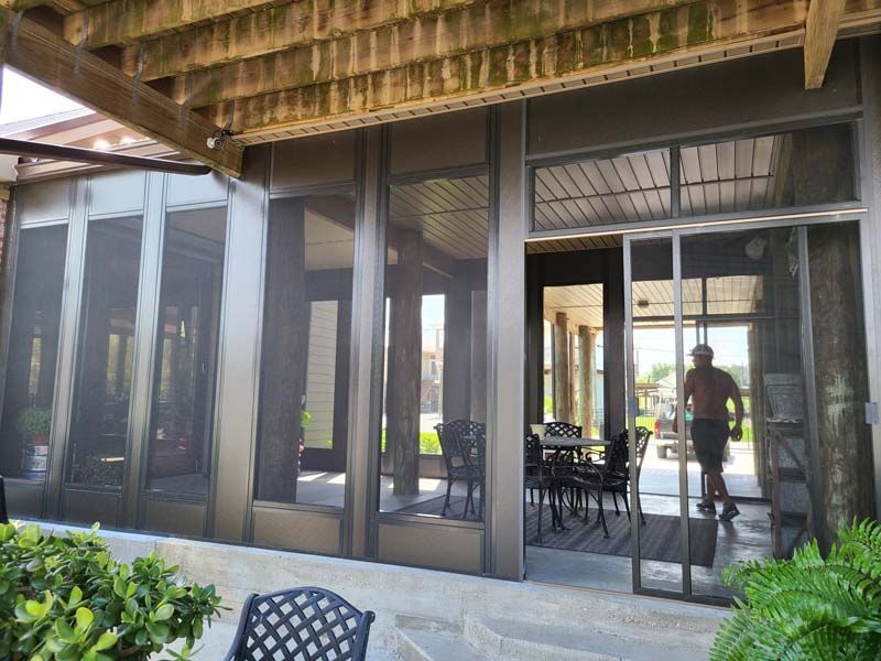 Outdoor patio with glass doors, wooden roof, and a person standing inside near dining tables.