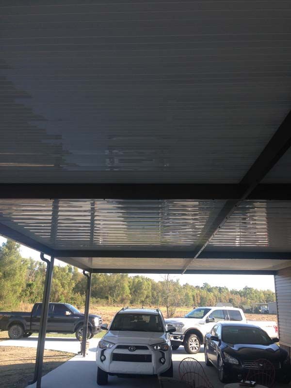 Covered parking area with several parked vehicles, including a white SUV and black truck.