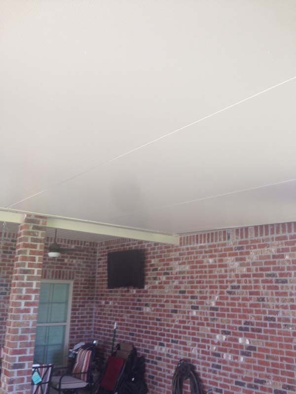 Brick porch with a screen door, stacked chairs, and a brick wall under a white ceiling.