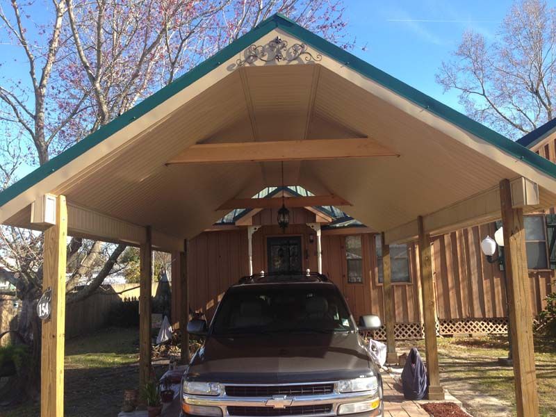 Silver pickup truck parked under a wooden carport with a gabled roof