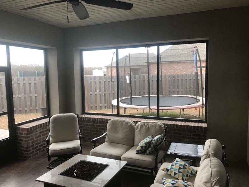Covered patio with outdoor seating, fire pit, and a trampoline visible through large screened windows.