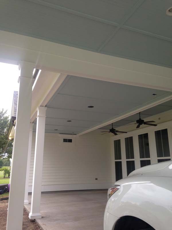 Covered porch with white columns, ceiling fans, and a partial view of a white car.