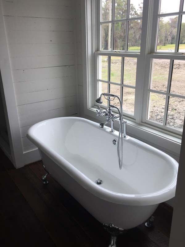 White clawfoot bathtub beside a window in a bright bathroom