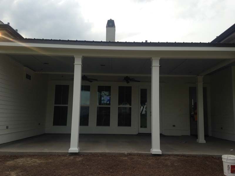 Covered front porch of a house with white columns and double glass doors.
