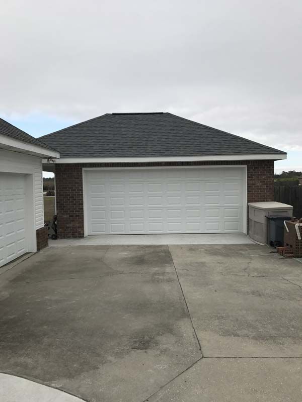 Suburban driveway with a two-car garage and gray concrete driveway under overcast sky
