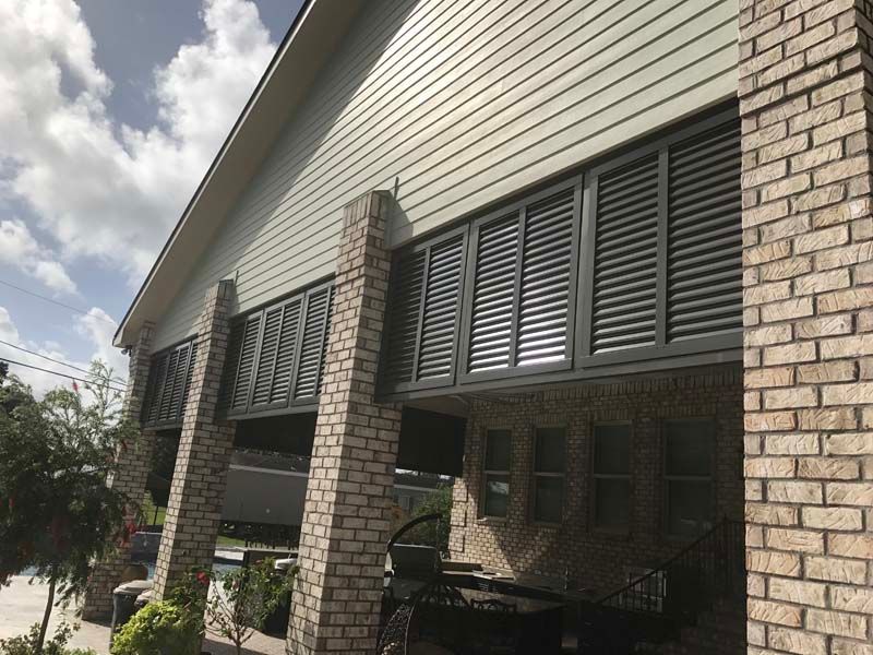 Brick house exterior with green shutters and a covered porch under a cloudy sky