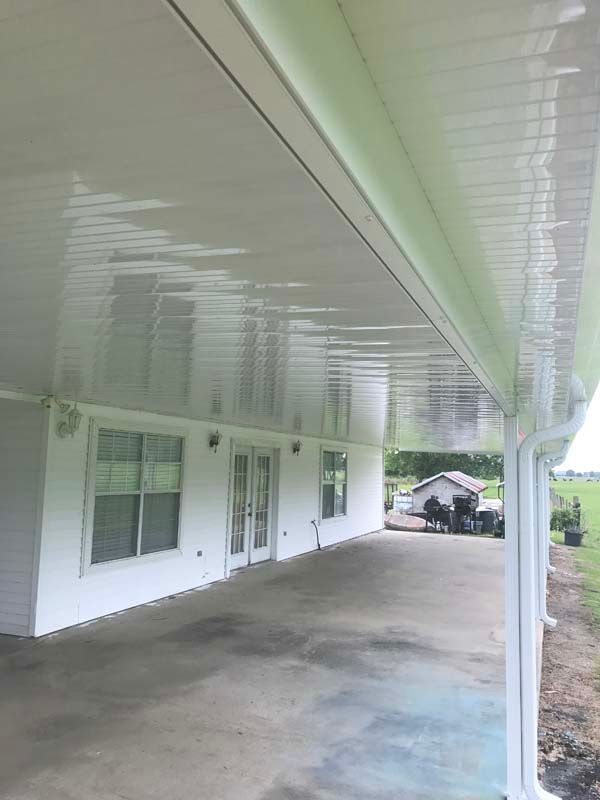 Covered porch with white siding, windows, and columns on a concrete patio.