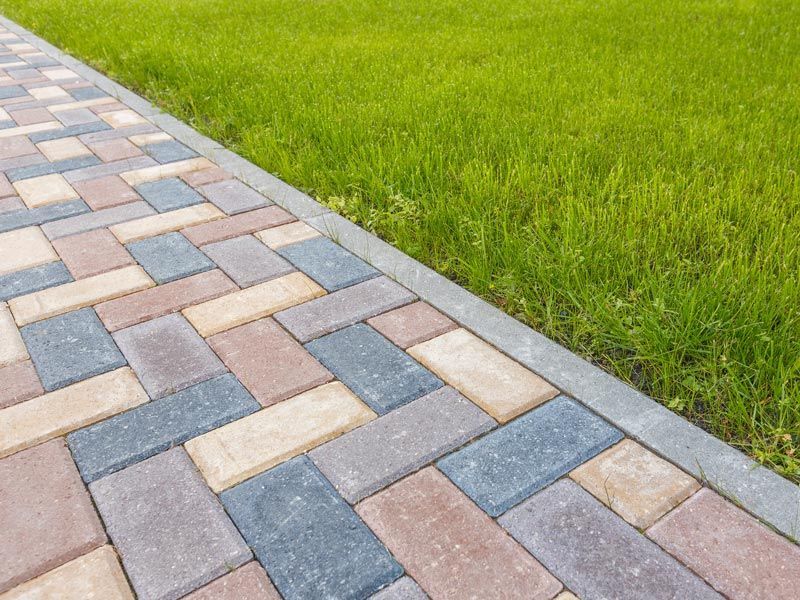 Colorful brick walkway beside a bright green grass lawn