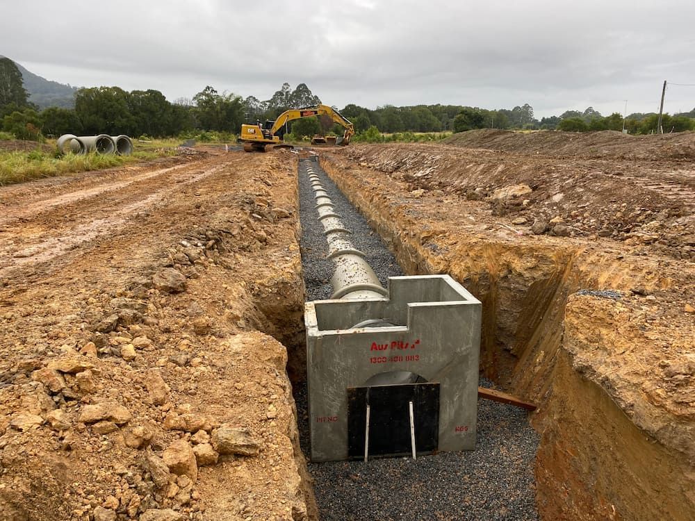 A Pipe Is Being Installed in A Trench in The Dirt — J & M Bashforth & Sons In Brunswick Heads, NSW