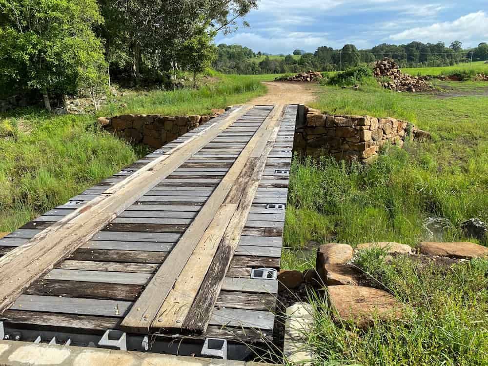 A Wooden Bridge Over A River In The Middle Of A Field — J & M Bashforth & Sons In Brunswick Heads, NSW