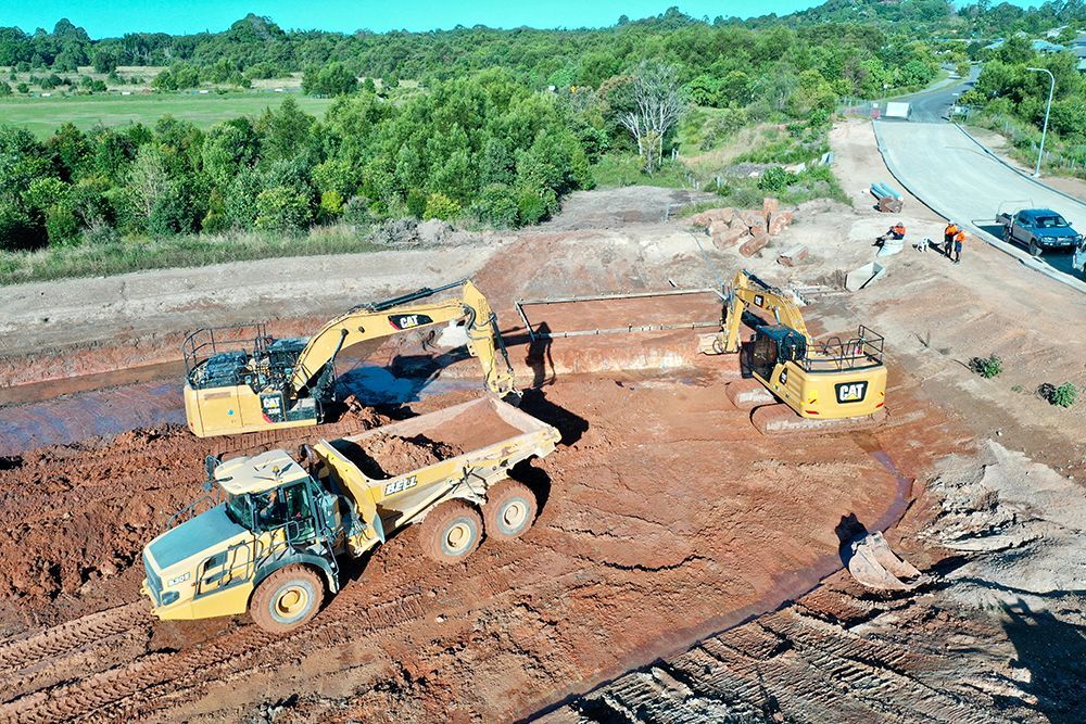 Aerial view of excavators and a dump truck on a civil construction earthworks site.