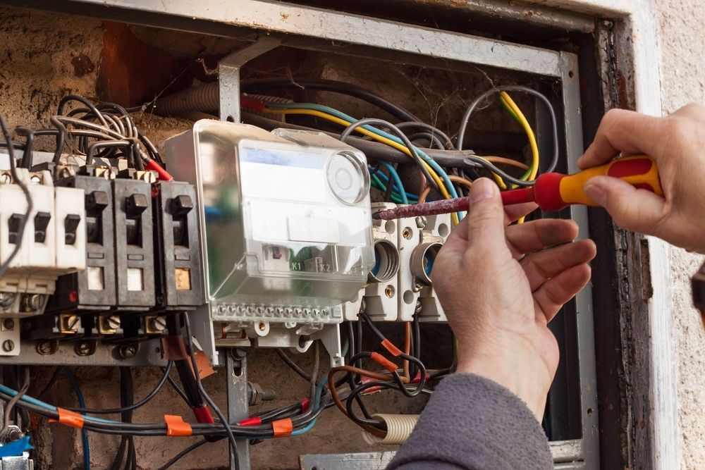 Electrician Using a Screwdriver to Work on a Fuse Box — A Step Above Electrical & Air Conditioning In Edmonton, QLD