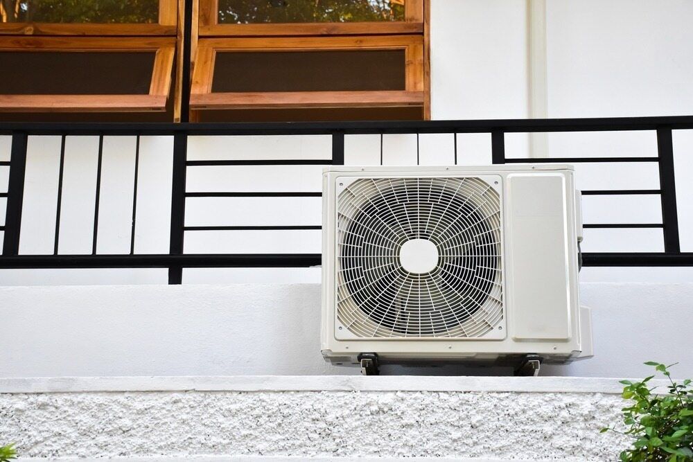 Outdoor Air Conditioning Unit Mounted on a White Wall — A Step Above Electrical & Air Conditioning In Edmonton, QLD