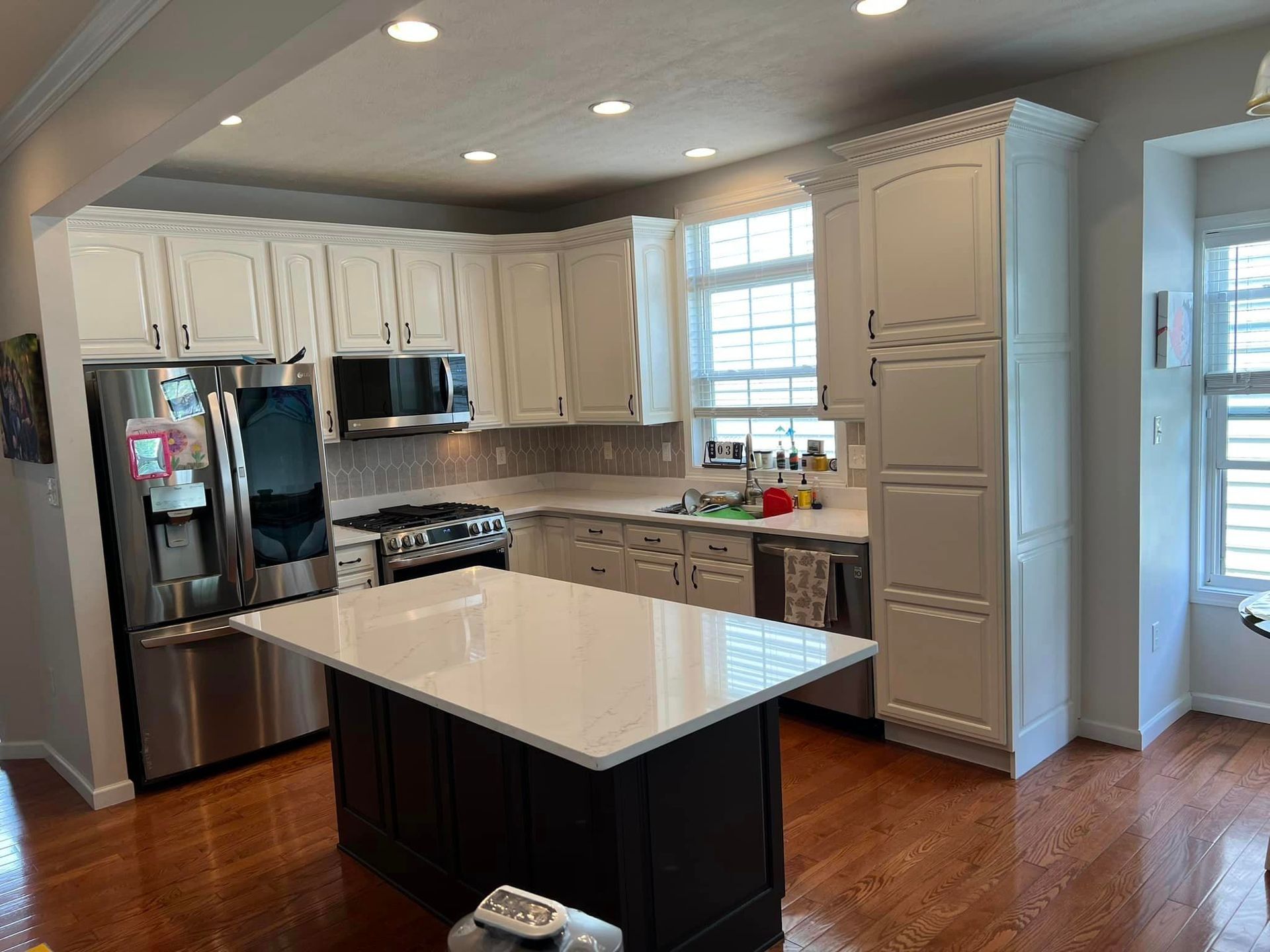 Small kitchen island with large overhanging countertop and pergo floors. New cabinets installed for kitchen remodel