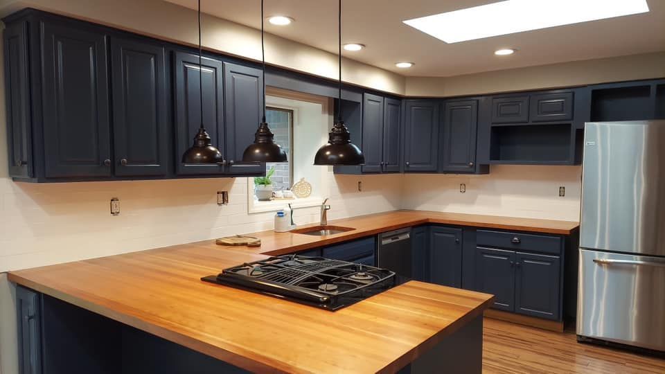 Beautifully remodeled kitchen with blue cabinets, butcher block countertop and stainless steel kitchen appliances