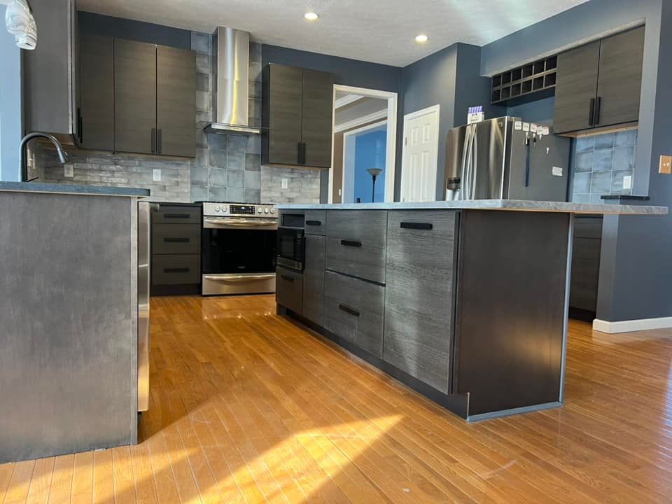 new grey modern kitchen cabinets with hardwood floors and a stone backsplash
