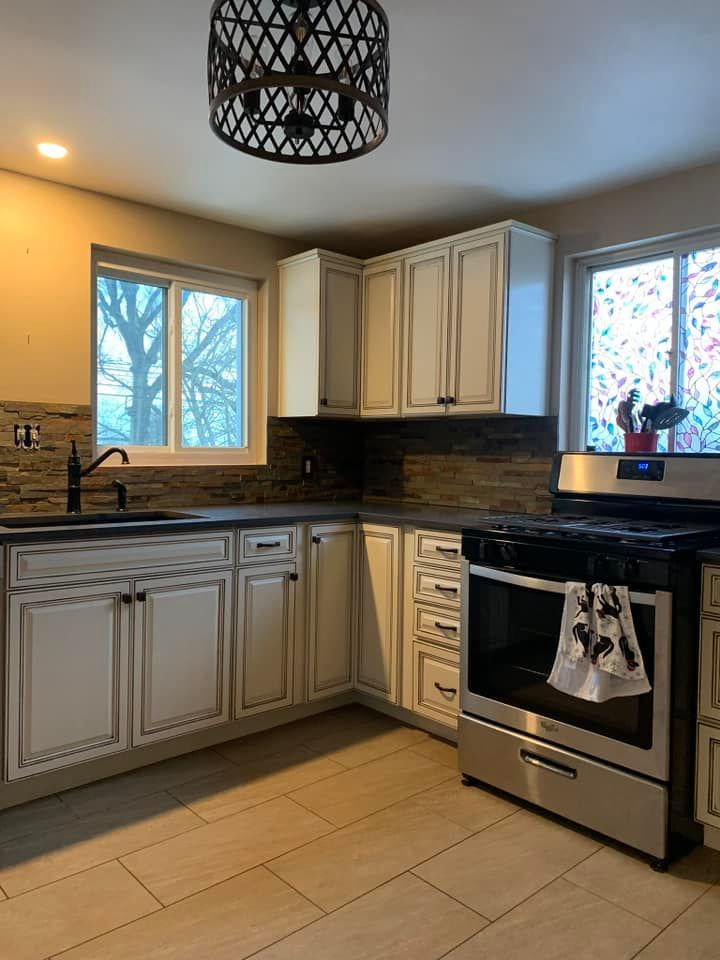 kitchen cabinets with stainless steel appliances, stone backsplash, and new light fixtures for home kitchen remodel
