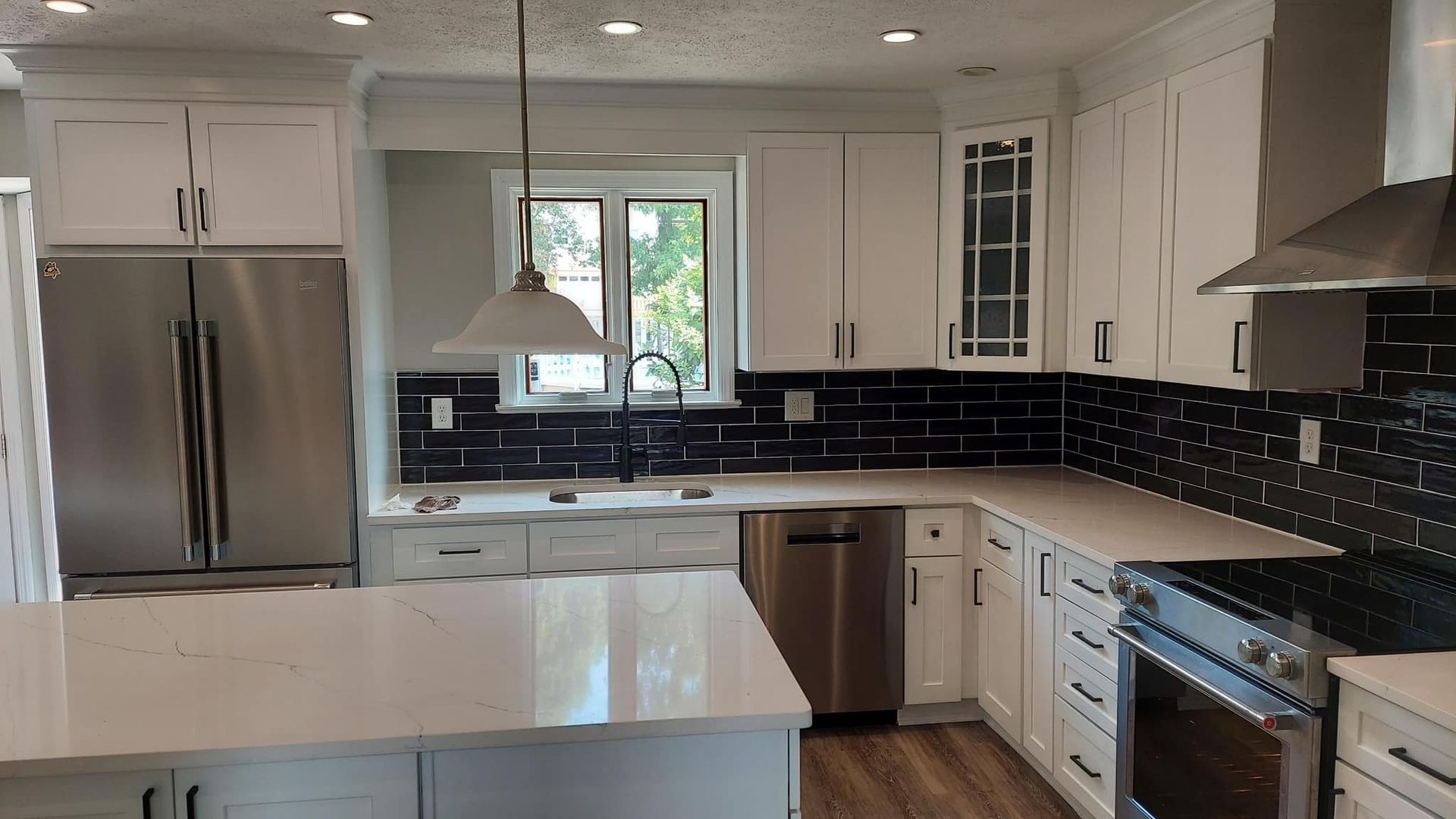 new white countertops, white kitchen cabinets, all new stainless steel appliances and backsplash