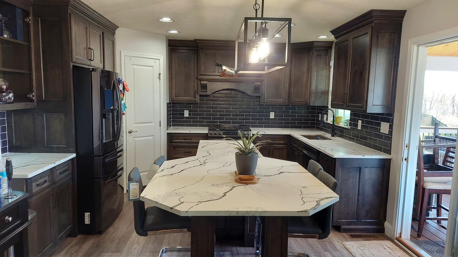 kitchen remodeled with new marble countertops, black tile backsplash and brown cabinets on the walls and island