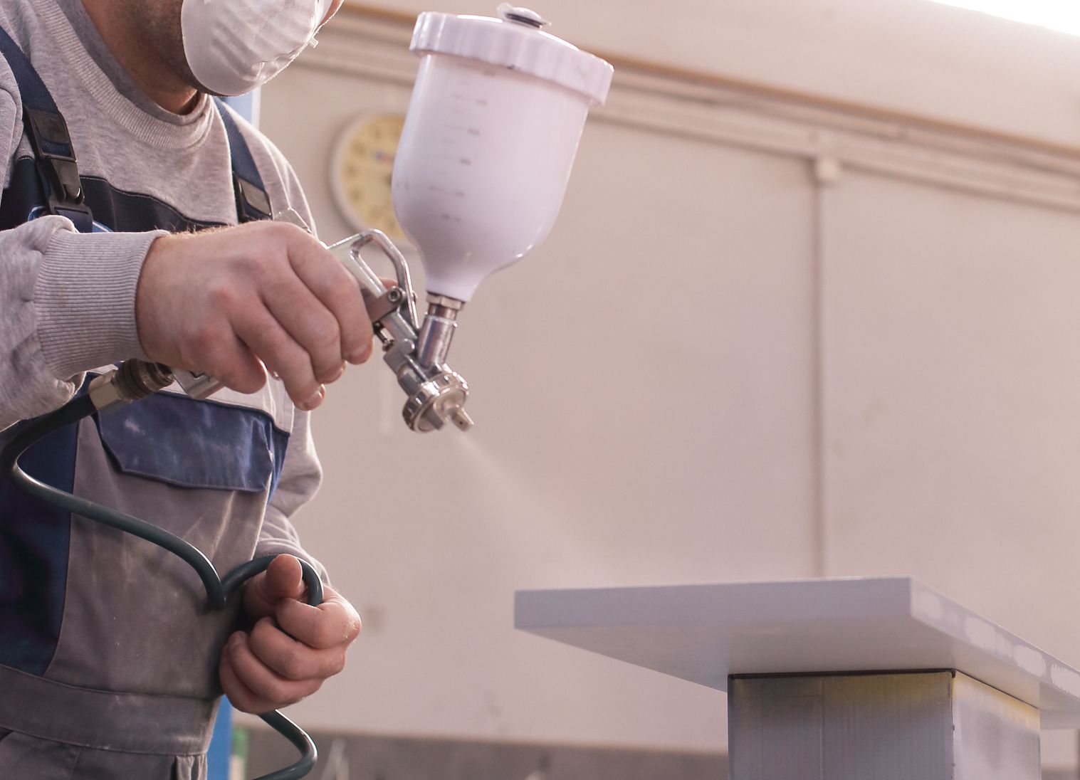 man spraying kitchen door front from a kitchen cabinet refinishing project