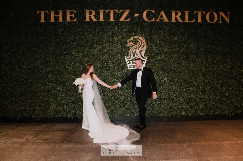 A bride and groom are holding hands in front of the ritz carlton hotel.