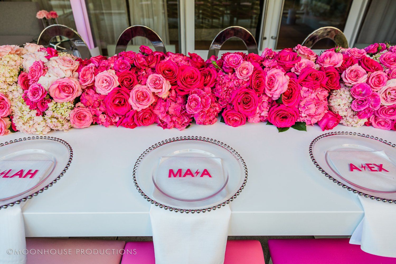 A table with three plates and pink flowers on it