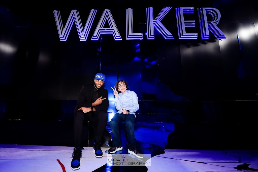 Two men are sitting under a sign that says walker