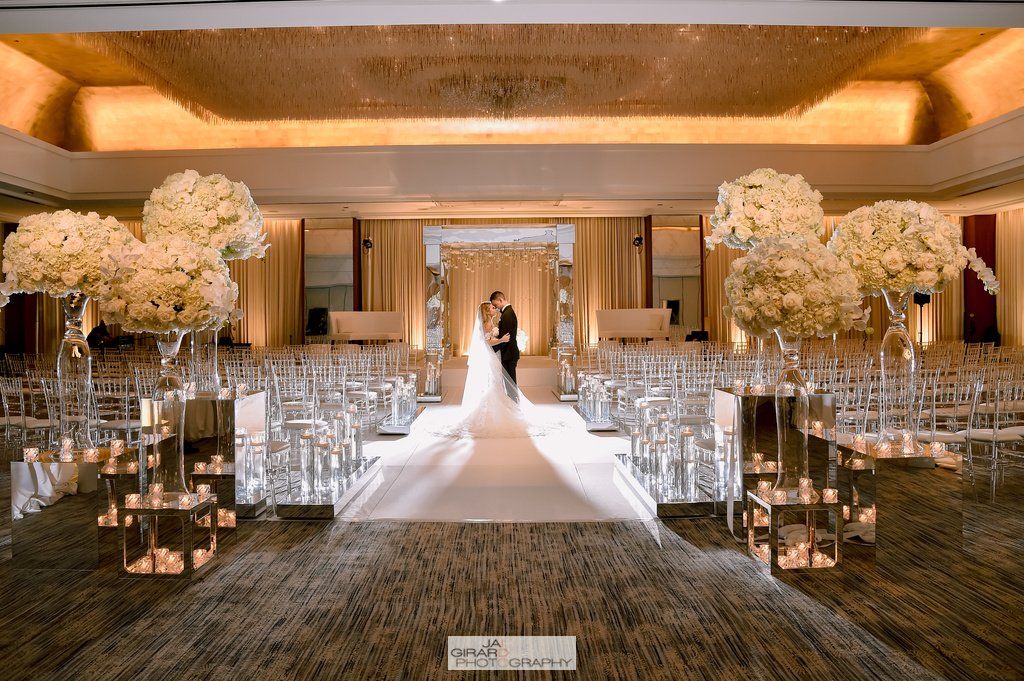 A bride and groom are walking down the aisle at a wedding ceremony in a large room.