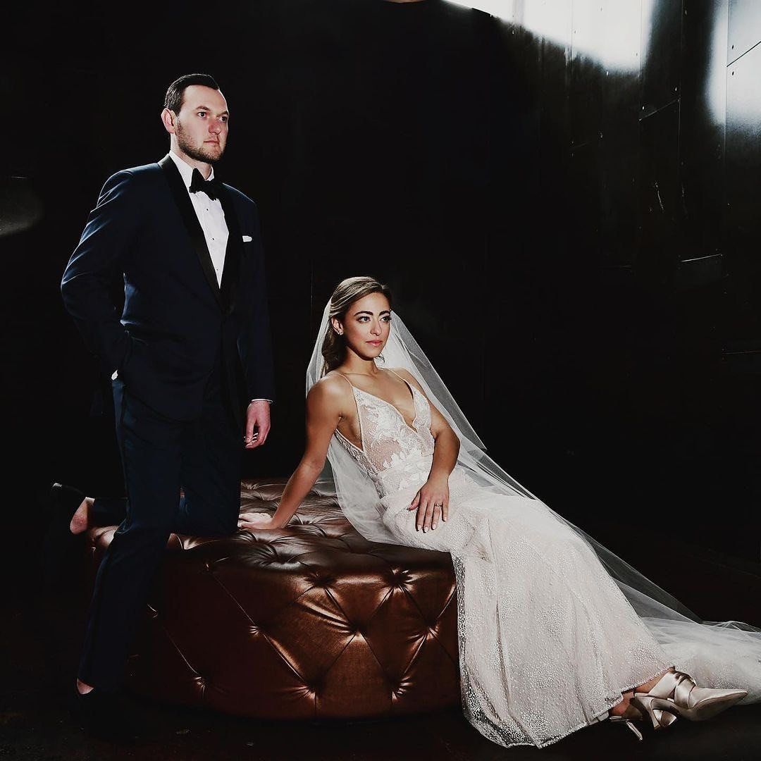 A bride and groom pose for a picture in a dark room