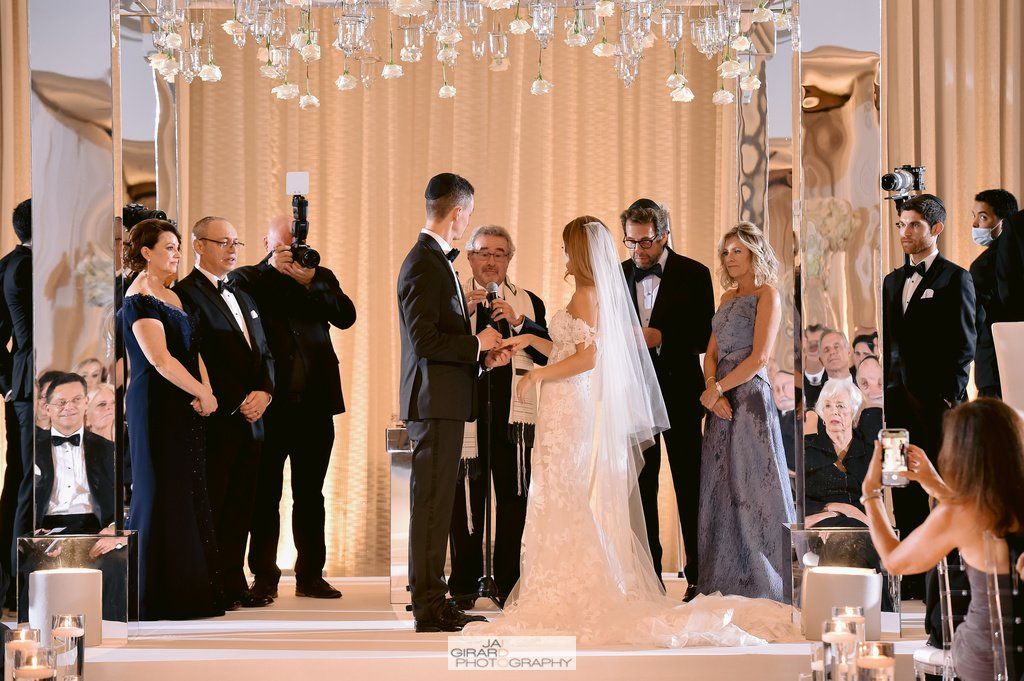 A bride and groom are getting married in front of a crowd of people at a wedding ceremony.