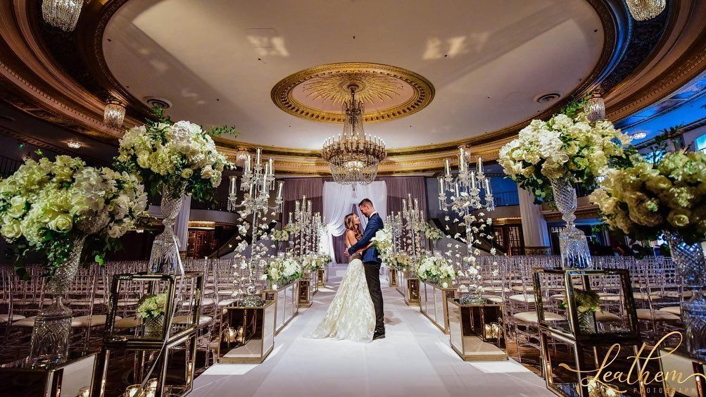 A bride and groom are kissing on the aisle of a wedding ceremony.