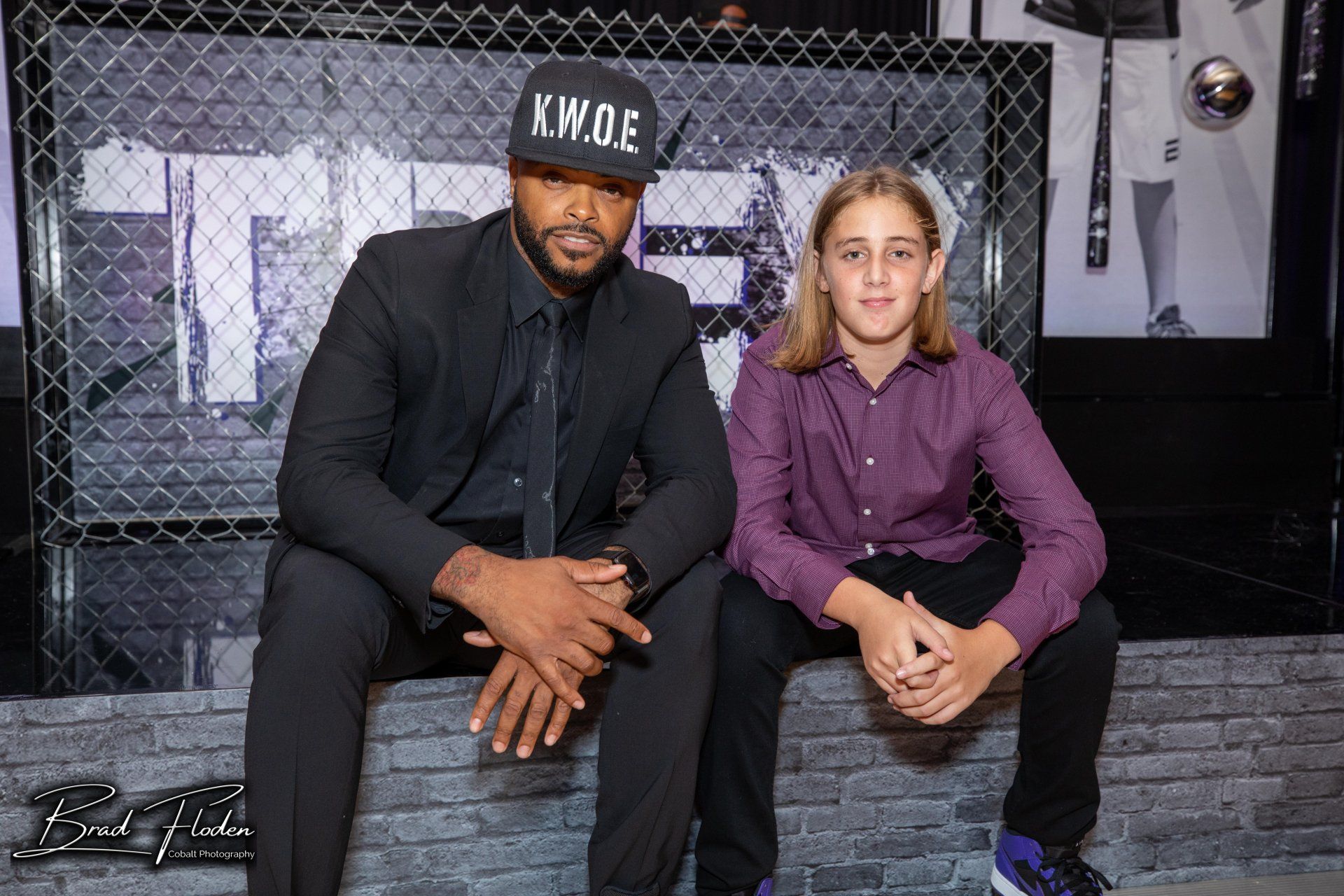 A man and a boy are sitting next to each other on a brick wall.