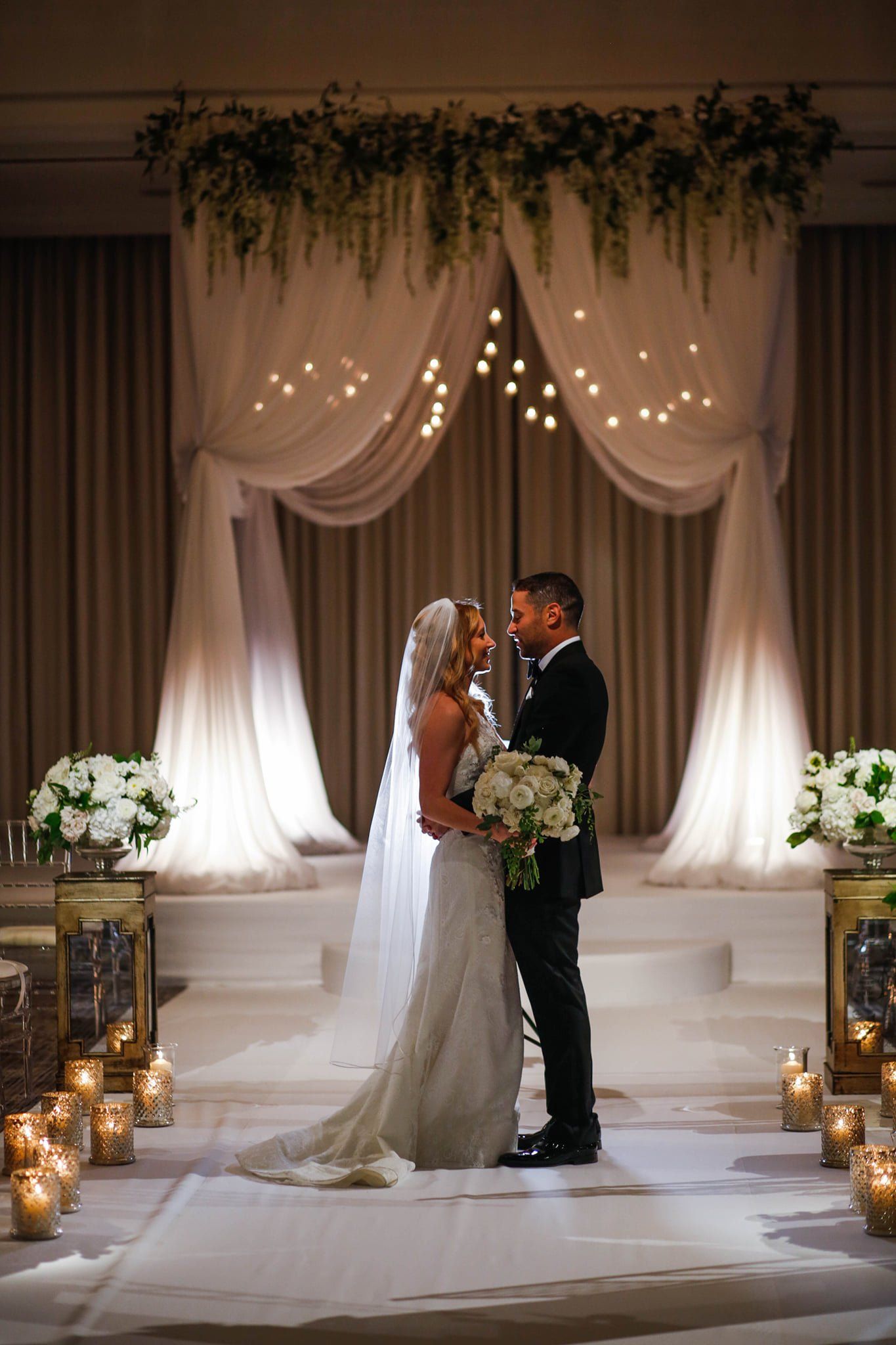A bride and groom are kissing at their wedding ceremony.