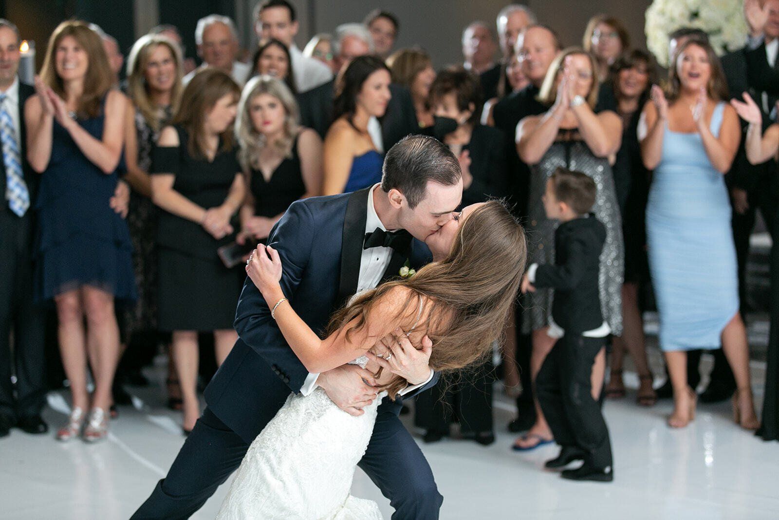 A bride and groom are kissing on the dance floor at their wedding reception.