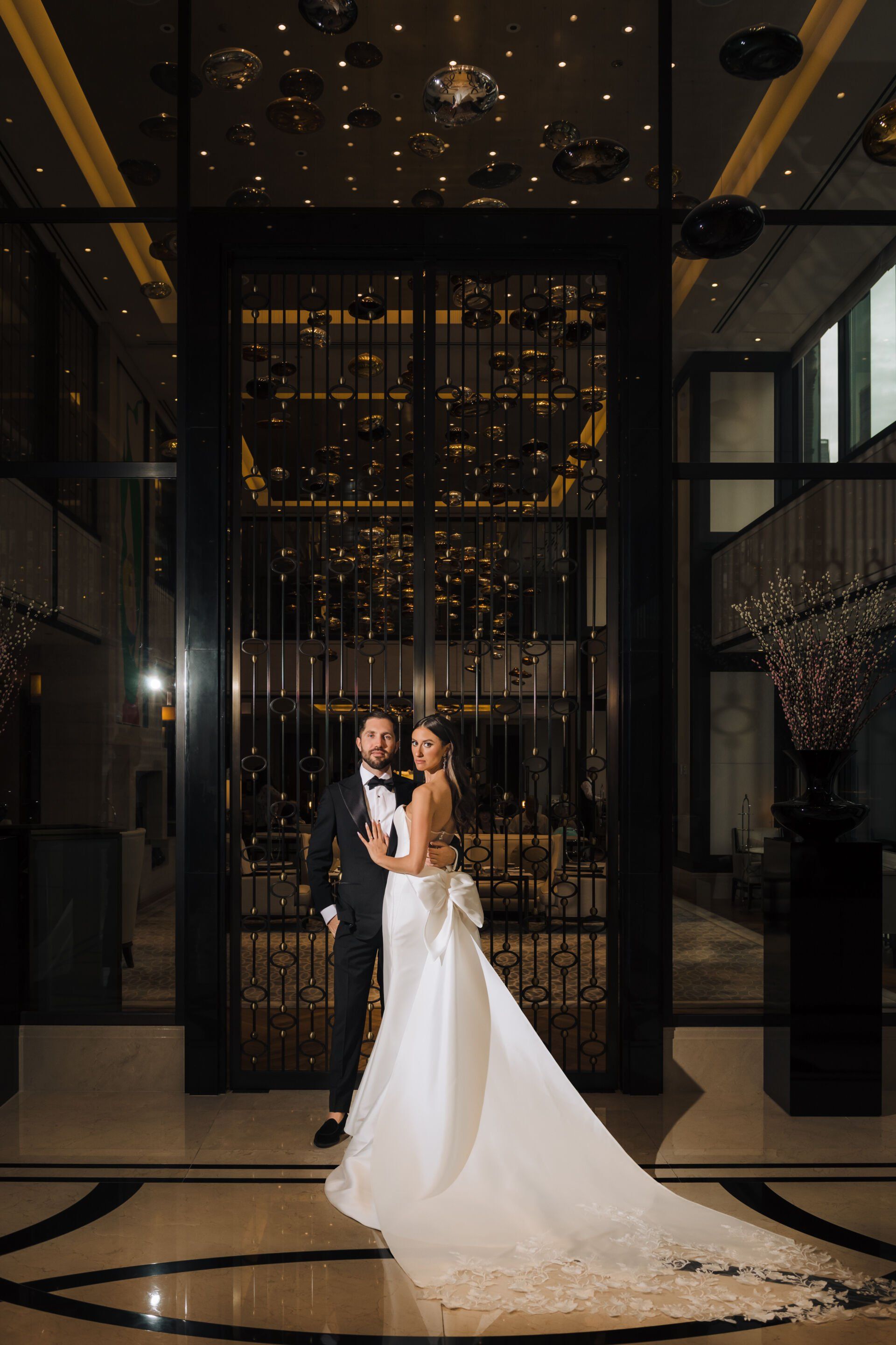 A bride and groom are posing for a picture in a hotel lobby.