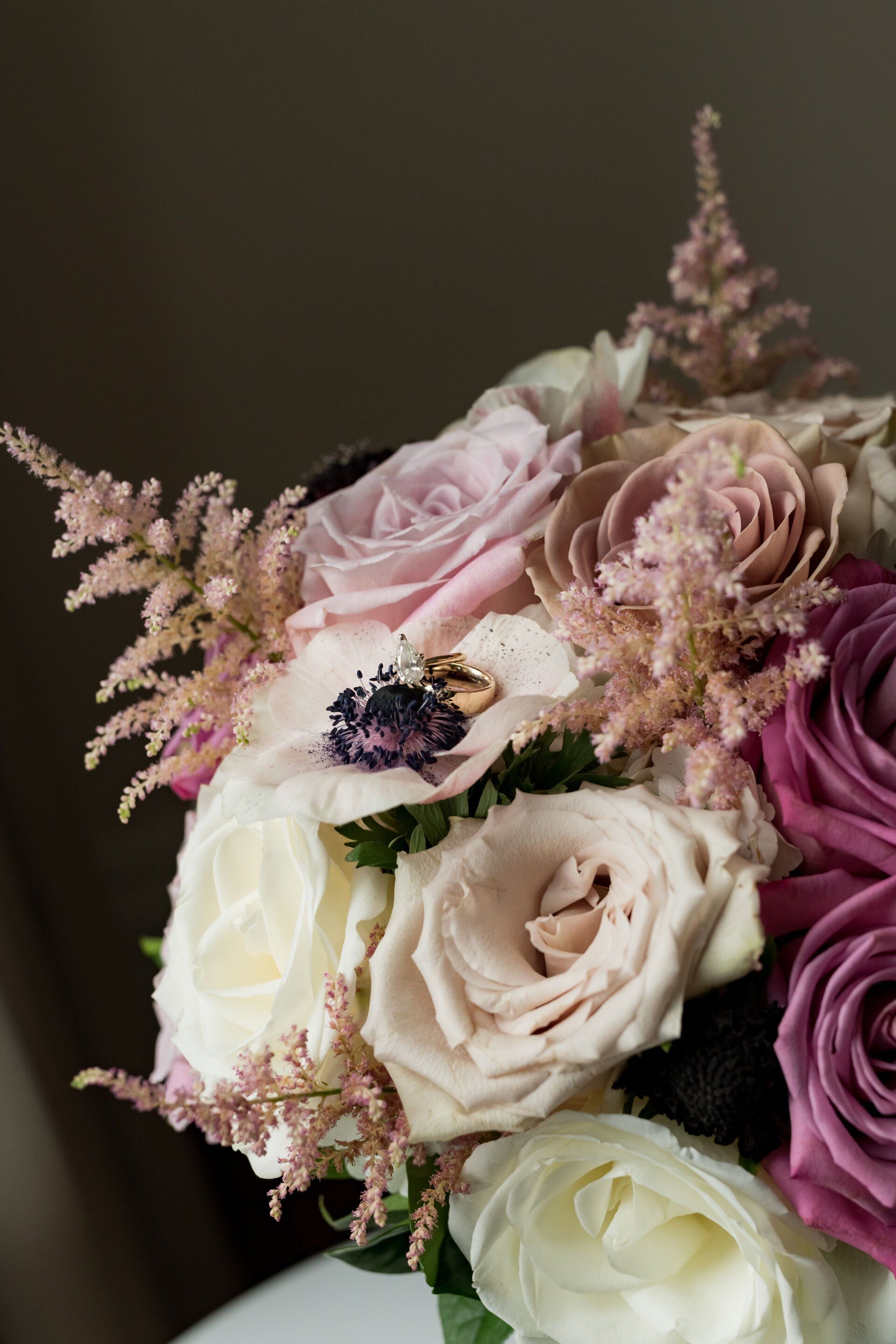 A close up of a bouquet of flowers with wedding rings on it.