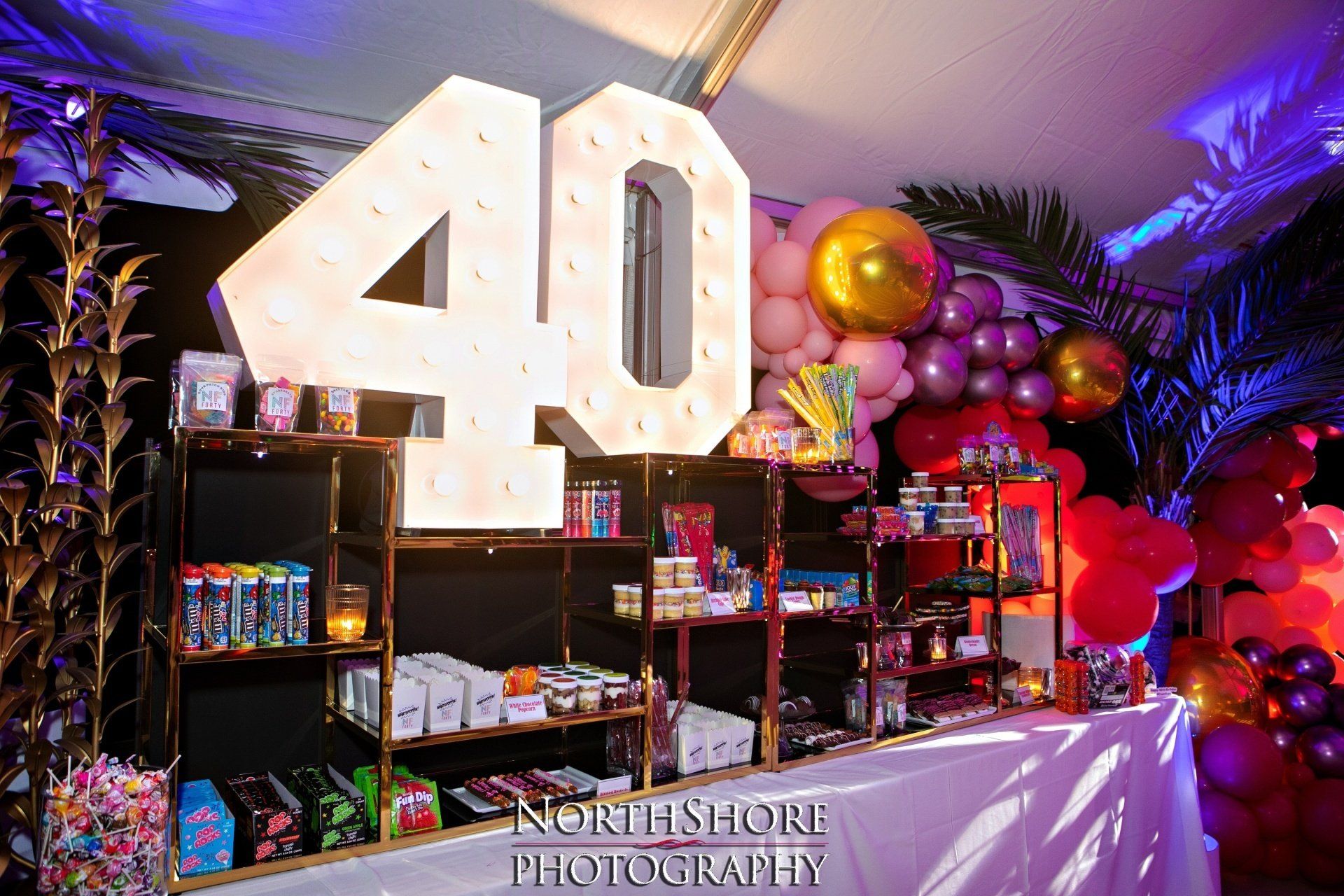 A 40th birthday party is being held in a room with balloons and candy.