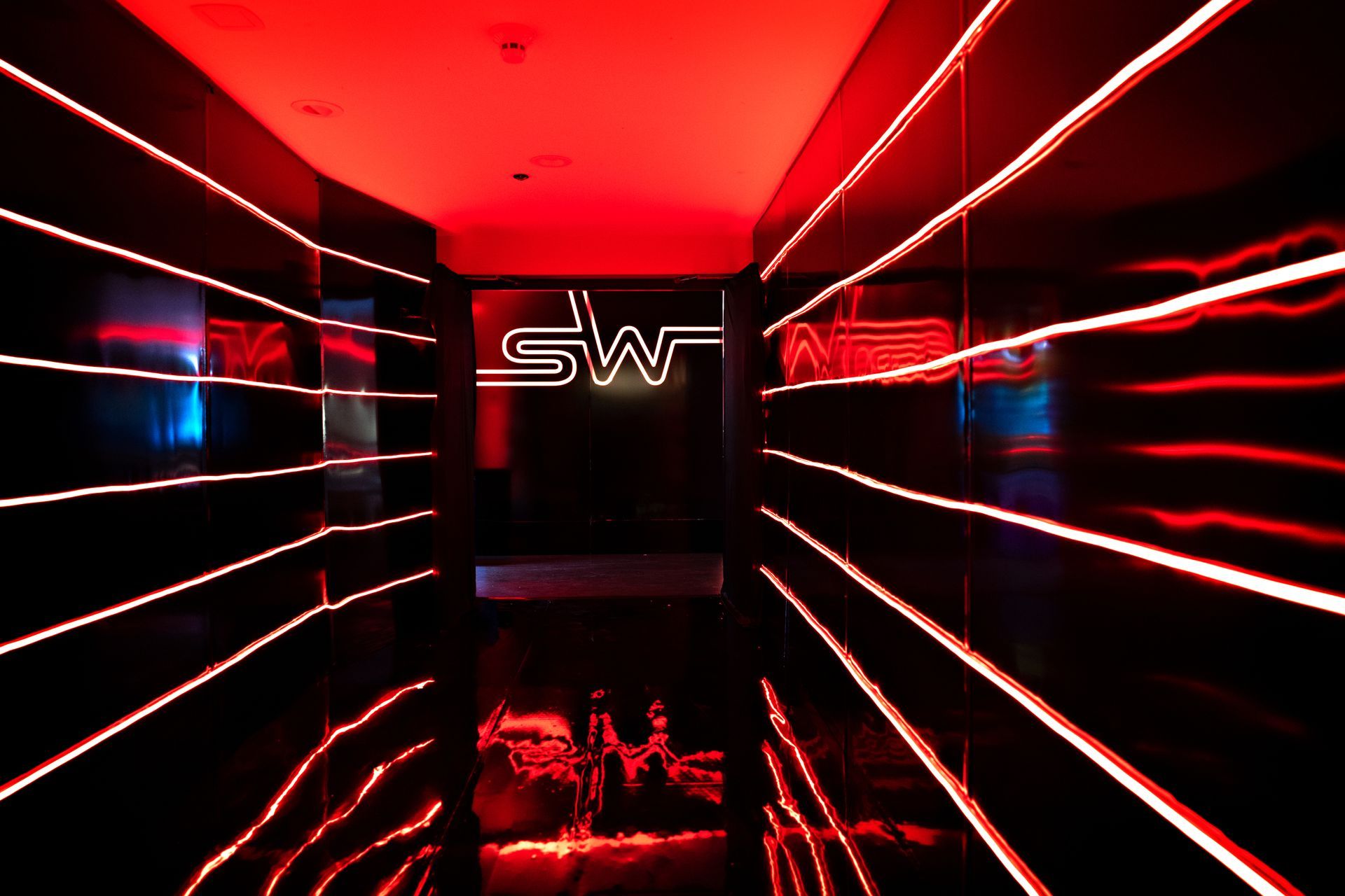 A dark room with a neon sign that says sw