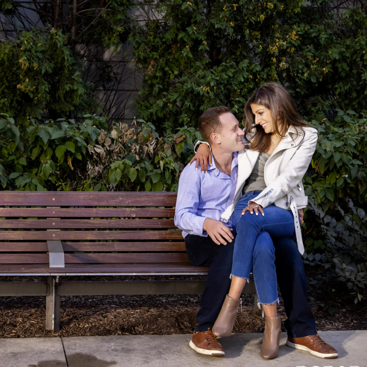 A man and a woman are sitting on a wooden bench